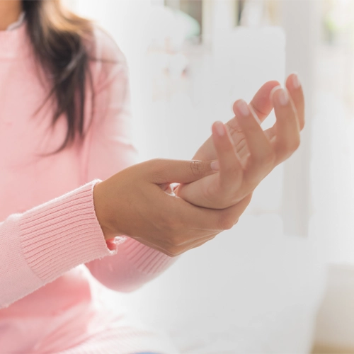 A young woman grasps her wrist and hand in pain.